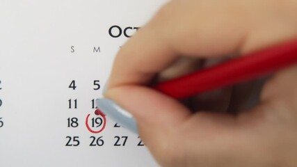 Female hand circle day in calendar date with a red marker. Business Basics Wall Calendar Planner and Organizer. October 19th
