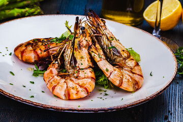 Grilled tiger prawns with greens on white plate