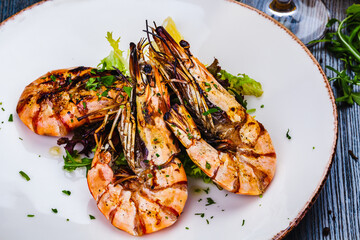 Grilled tiger prawns with greens on white plate