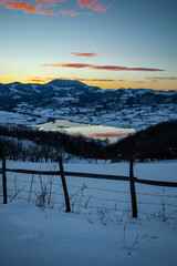 Colorful sunset evening at mountain lake in snow, beautiful nature winter scene