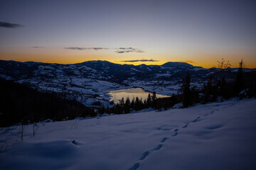 Colorful sunset evening at mountain lake in snow, beautiful nature winter scene