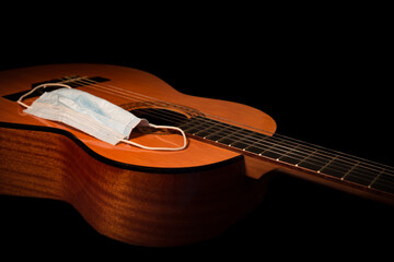 Obraz premium Guitar body and neck with Face Mask - Virus Concept. Shot in the studio with warm lighting on a black background, this image could be for covid-19 coronavirus restrictions for events, shows and gigs