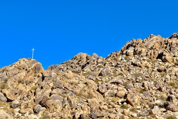 Fototapeta premium Religious Cross on Rocky Mountain in Desert City 
