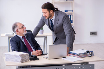 Fototapeta premium Old boss and his young assistant working in the office