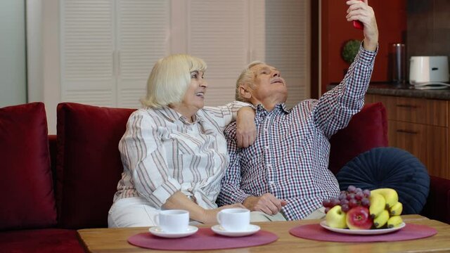 Happy senior family having fun, making selfie photos together on smartphone at home. Laughing bonding mature older married couple using funny mobile phone applications or recording video. 6k downscale