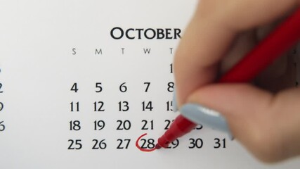 Female hand circle day in calendar date with a red marker. Business Basics Wall Calendar Planner and Organizer. October 28th