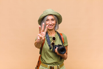 middle age woman smiling and looking friendly, showing number three or third with hand forward,...