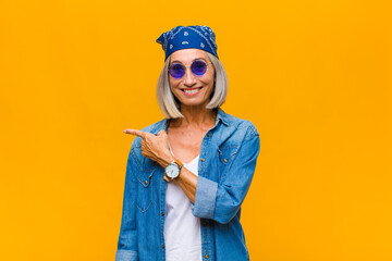 middle age woman looking excited and surprised pointing to the side and upwards to copy space