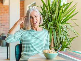middle age woman feeling confused and puzzled, showing you are insane, crazy or out of your mind