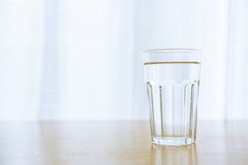 Drinking water in a drinking glass on the wooden table close up with copyspace. Purity water in a...