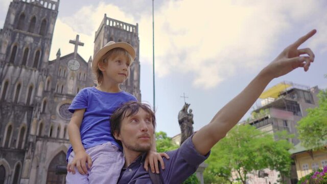 Happy tourists father and son visit famous destination in Hanoi city - St. Joseph's Cathedral. Travel to Vietnam concept