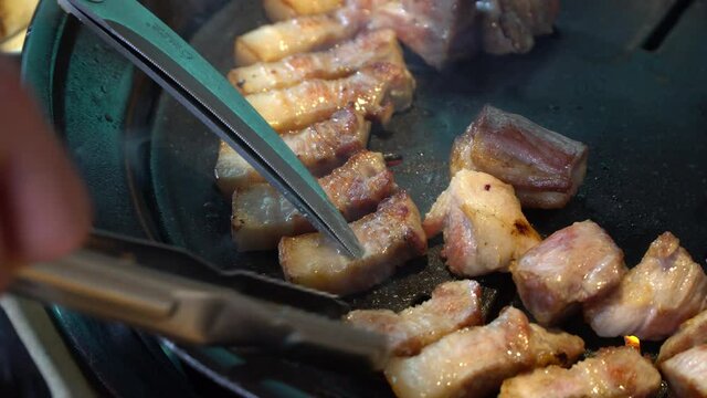 Close up of fat pork belly sizzling on traditional Korean grill