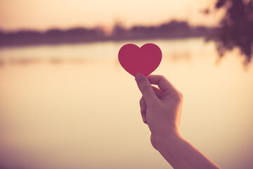 Silhouette broken heart, close up woman hand holding broken heart in the park.
