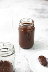 Chocolate Almond butter in jars that focus on the full one in isolated white background. Selective focus