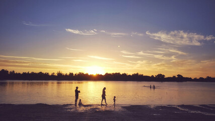 Fototapeta premium Siluetas de una familia en la playa al atardecer