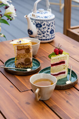 afternoon tea on the roof terrace. assorted cakes and fresh green tea in a teapot on a wooden table