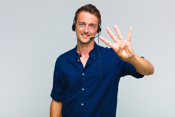 young handsome man smiling and looking friendly, showing number four or fourth with hand forward,...