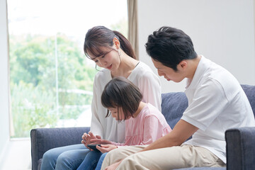 Fototapeta premium ソファーでスマートフォンを見る親子