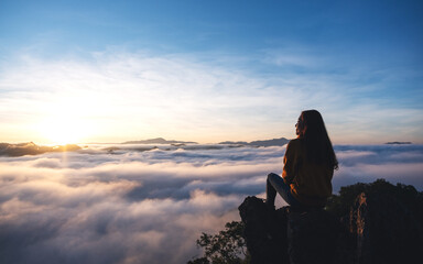 A female traveler sitting on the mountain peak, watching sunrise and sea of fog