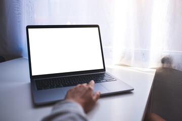 Mockup image of a businesswoman using and touching on laptop touchpad with blank white desktop screen on the table