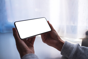 Mockup image of a woman holding mobile phone with blank white desktop screen