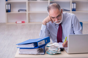 Old male accountant in budget planning concept in the office