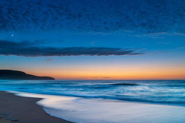 Fototapeta na wymiar High cloud, partial moon and a pretty blue dawn at the beach