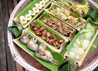 Many kinds of local Thai food in bamboo tubes cut in half, Secondary with banana leaf.