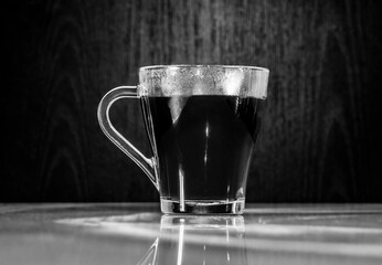 A glass with hot soaring tea on a black background.