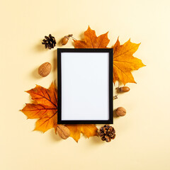Frame and autumn leaves and berries on a yellow background, mockup for design, place for text, concept of autumn. Copy space.
