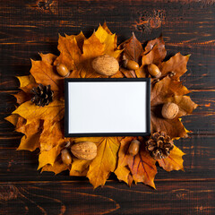 Frame and autumn leaves, nuts, cone and berries on wooden background, mockup for design, template place for text, concept of autumn. Copy space.