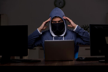 Male hacker hacking security firewall late in office