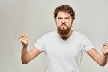 bearded man gesturing with his hands in a white t-shirt aggression light background