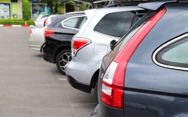 Closeup of rear side of black car and other cars parking in parking area.