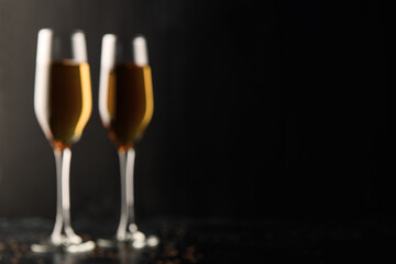Blurred background. Two glasses of champagne, wine on a black background, a place for text on the right, copypace. New year and Christmas background