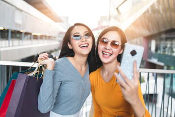Asain woman in shopping. Happy woman with shopping bags enjoying in shopping.lifestyle concept.Smiling girl  holding colour paper bag.Friend selfie from mobile and shared social neteork. © anon