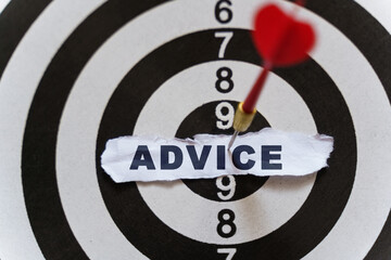 A piece of paper with the text is nailed to the target with a dart - ADVICE