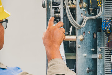 An electrician is inspecting the equipment in the field of the power sub-station.