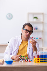 Young male chemist studying molecular model in the classroom