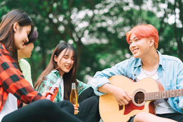 Fototapeta premium group of happy Asian young people sitting on the guitar and singing in the park