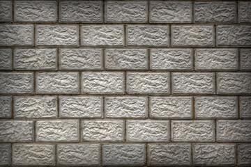 The wall of the house is made of gray concrete blocks. Aged background or wallpaper with vignetting.  The seams form a pattern similar to brickwork. Dramatic backdrop on the theme of home construction