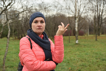 An adult woman with an expression of puzzlement and surprise looks at the camera in an autumn park