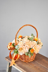 Fototapeta na wymiar Small flower shop and Flowers delivery. Flower arrangement in Wicker basket. Beautiful bouquet of mixed flowers in woman hand. Handsome fresh bouquet
