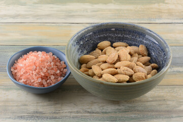 Himalayan pink salt and whole almonds salted with pink Himalayan salt in bowls on table