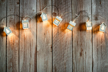New year christmas background, glowing garland houses on wooden background