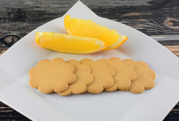 Orange and vanilla cookie biscuits with two orange slices on white snack plate