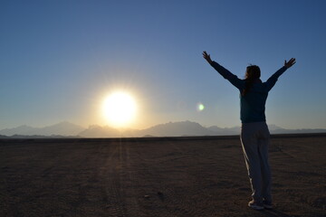 Fototapeta na wymiar Girl on the background of the sun in the desert