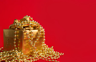 Gift box with bow and beads on a bright red background. Gift wrapping concept. Close-up. Selective focus.Place for text