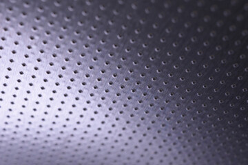 Dark metal wallpaper. Tinted violet or purple background. Perforated aluminum surface with many holes, hanging from above like a ceiling. Perforation rows go into the distance and form perspective