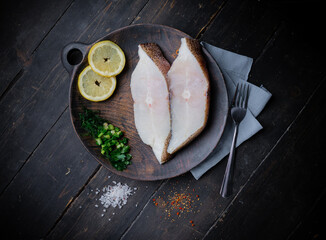 Frozen Greenland halibut steaks on the wood cutting board. Food background. Top view - obrazy, fototapety, plakaty